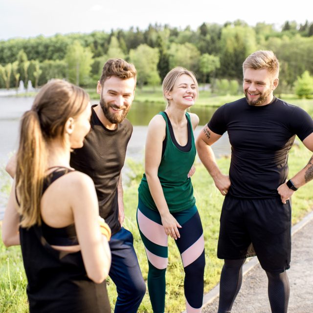 Sports team having fun standing together after the training outdors in the park near the lake