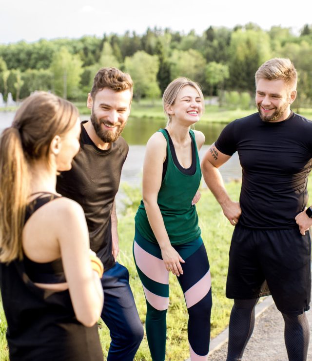 Sports team having fun standing together after the training outdors in the park near the lake